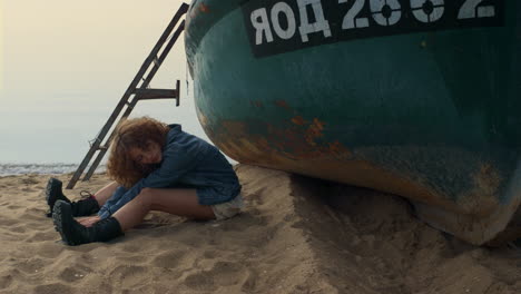 Woman-sitting-bending-body-to-legs-empty-seashore.-Curly-woman-relax-on-beach.