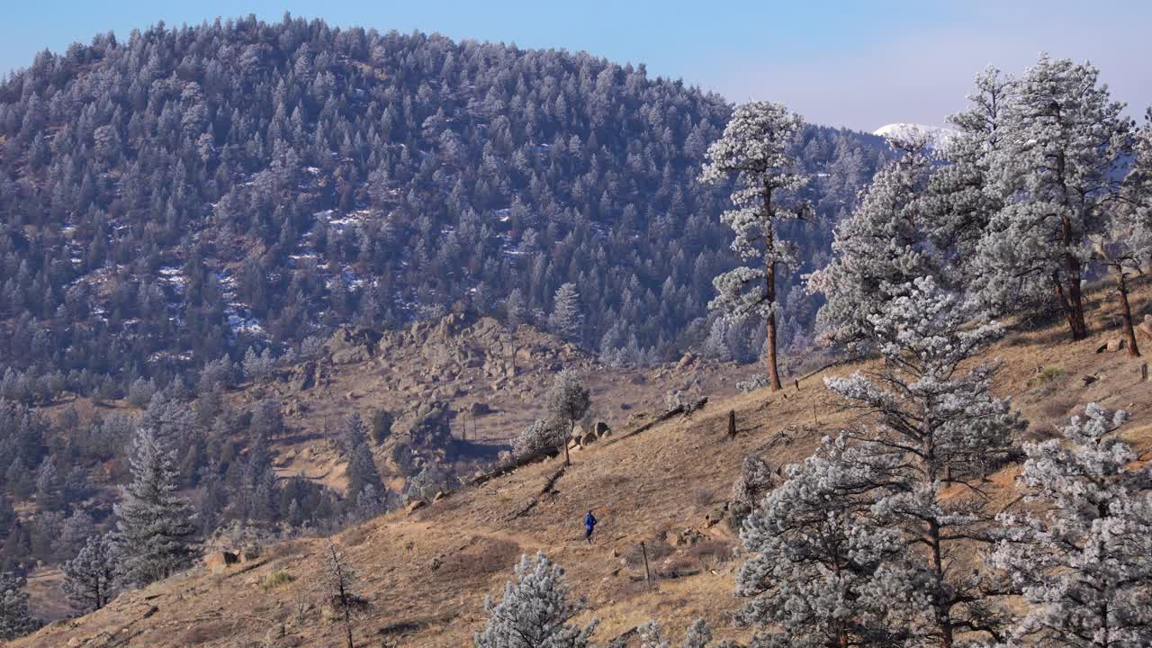mujer corriendo por un sendero accidentado en las montañas rocosas