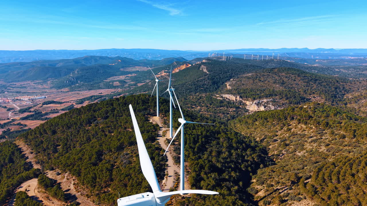 Alicante, Espanha, 8 de agosto de 2025: Vista aérea de turbinas eólicas em colinas arborizadas na Espanha. Turbinas eólicas brancas em cristas de montanhas verdes sob céu azul claro na Espanha rural. Imagem aérea.