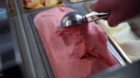 sirviendo helado de fresa rosa en una heladería italiana