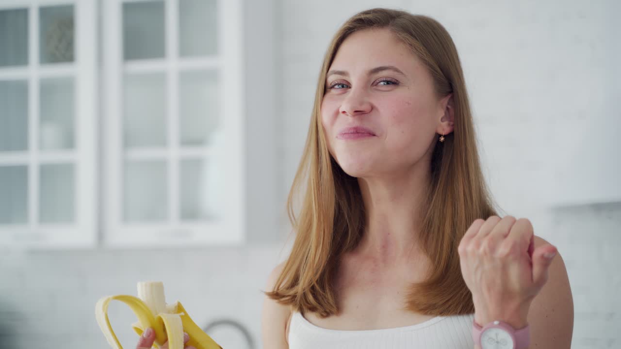 Woman having organic breakfast. Lifestyle portrait of young happy woman eating banana