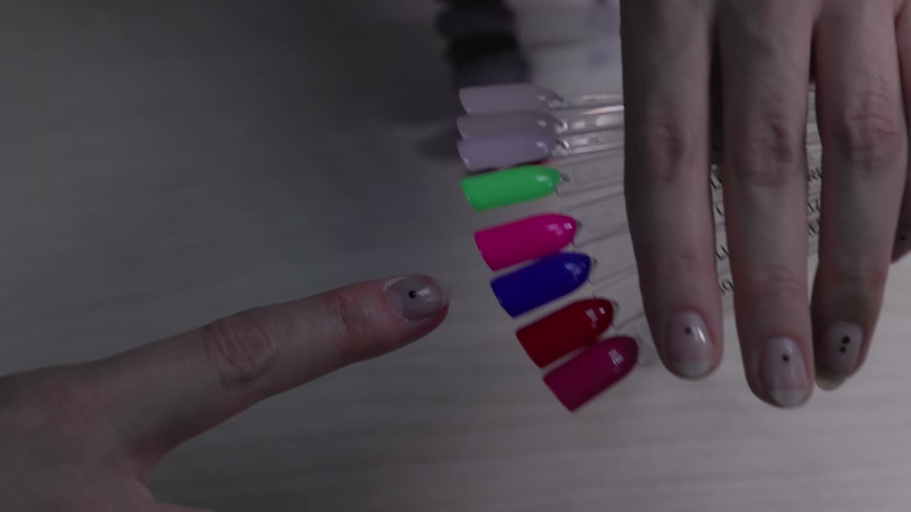 mujer eligiendo el color del esmalte de uñas para la manicura. selección del color de la laca de uñas. mujer eligiando el color de las uñas de tester.