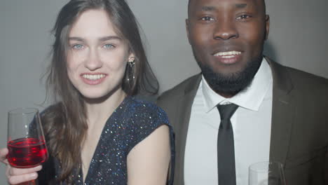 Tipsy-Multiethnic-Couple-Posing-with-Drinks-at-Party