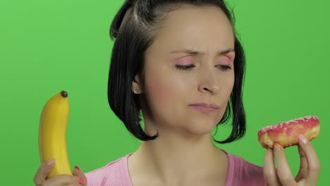 woman choosing between a banana and a donut