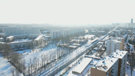 scene at gdansk city during winter with snowy road, field and buildings at daytime in poland