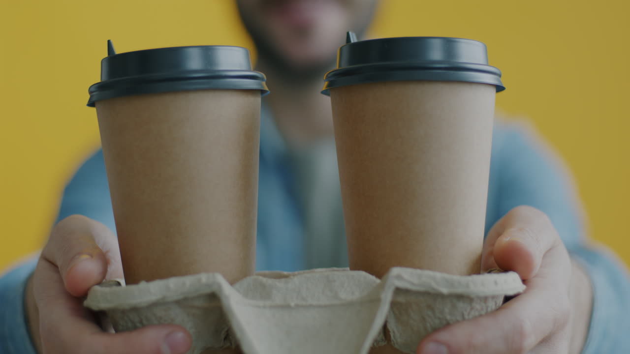 Two Paper Coffee Cups Being Held