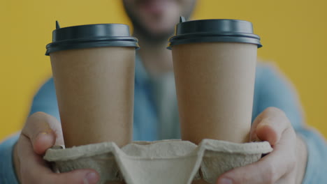 two paper coffee cups being held