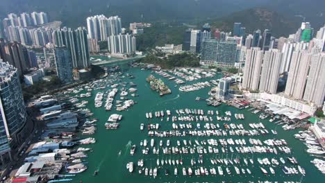 hong kong marina and typhoon shelter with skyscrapers and hundreds of small boats on a clear summer day, aerial pull up view.