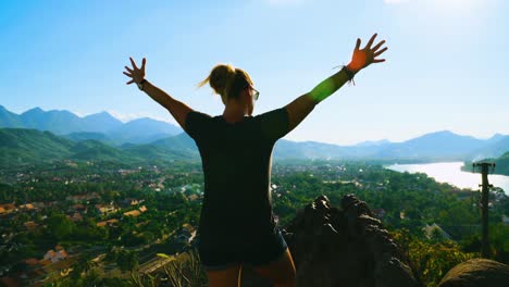 back view of female traveler enjoying wanderlust spending on feeling free rising arms with accomplishment. tracking right