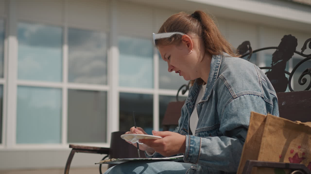 Female annotating thoughts. Young woman writing in journal. Girl recording observations in urban environment. Young lady with denim jacket journals while contemplating cityscape around her