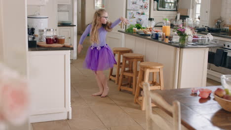 happy ballerina girl dancing in kitchen having fun practicing ballet dance moves wearing purple tutu at home