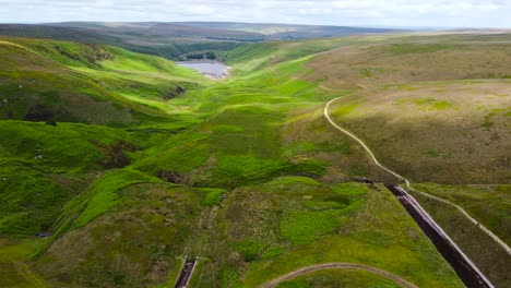 Aerial-view-above-lush-green-Peak-district-trekking-countryside-valley-towards-Marsden-moor-lake