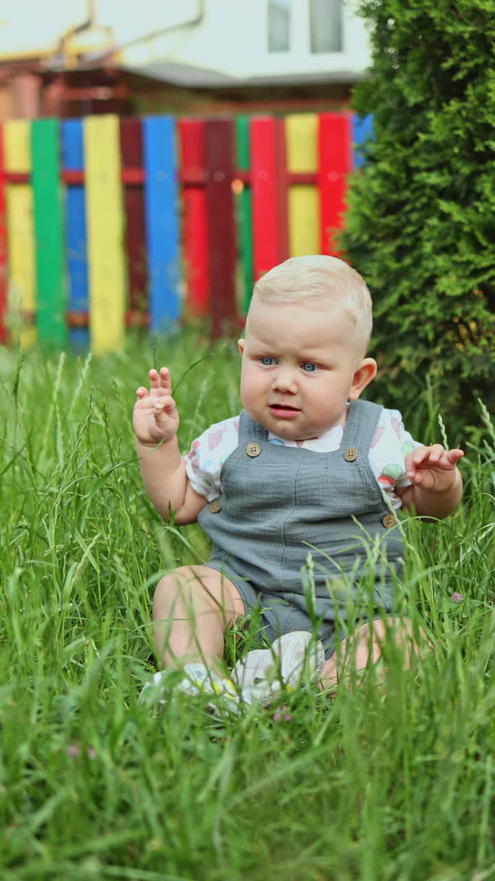 Ein zehn Monate alter Junge spielt sitzend auf dem Gras. Ein Kind in der Natur.