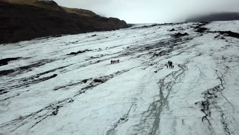 Luftlandschaftsansicht-Von-Menschen,-Die-Im-Sommer-Auf-Dem-Sólheimajökull-gletscher,-Island,-Spazieren-Gehen