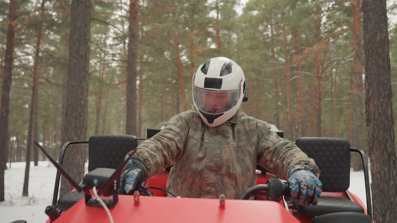 Un pilota entusiasta si prepara per un viaggio sulla neve. L'avventuriero si attrezza per un giro in quad invernale nei boschi innevati. Il pilota è equipaggiato per un'emozionante corsa in veicolo fuoristrada attraverso la foresta innevata durante l'inverno.