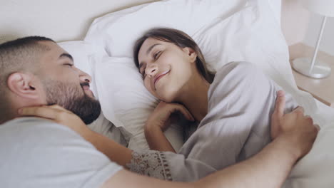 사랑하는 커플이 침대에 누워서 서로 잘 키스하고 있습니다.