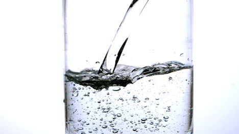 water being poured into a glass on white background