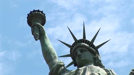 Die-Freiheitsstatue-Mit-Hochgehaltener-Fackel-Steht-Vor-Einem-Blauen-Himmel-Voller-Wolkenfetzen