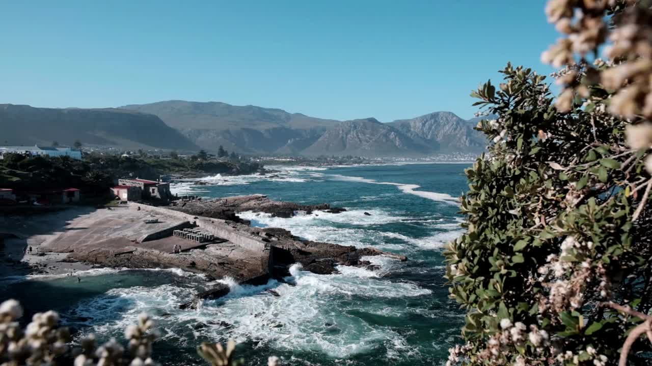 Old harbour in Hermanus South Africa with waves crashing and mountain views
