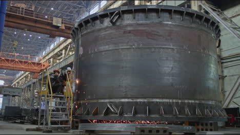 welding a large metal tank in a factory