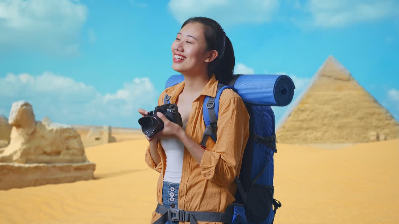 Side View Of Asian Female Hiker With Mountaineering Backpack Smiling And Holding A Camera In Her Hands Then Looking Around While Traveling In Pyramid Of Giza