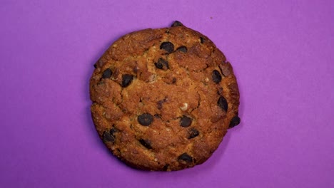 una galleta de chocolate en primer plano, una foto macro, girando rápidamente sobre un fondo púrpura giratorio.