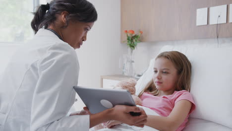 médico visitando a la madre y la hija acostadas en la cama en la sala del hospital usando una tableta digital