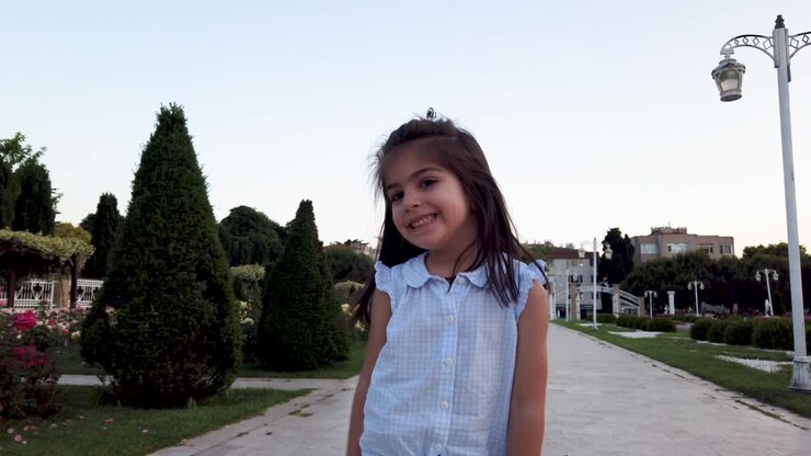 Niña graciosa actuando frente a la cámara en el parque