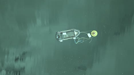 rising top down aerial view of a dinghy attached to a buoy off of ireland's coast