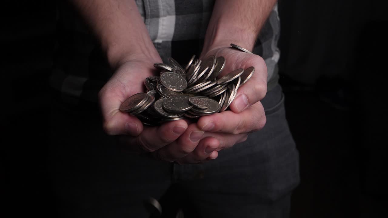 남자는 그의 손으로 위에서 비가 내리는 동전을 잡으려고 한다