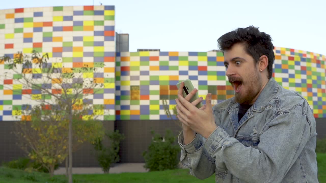 joven mira el teléfono y celebra a lo grande una noticia o resultado