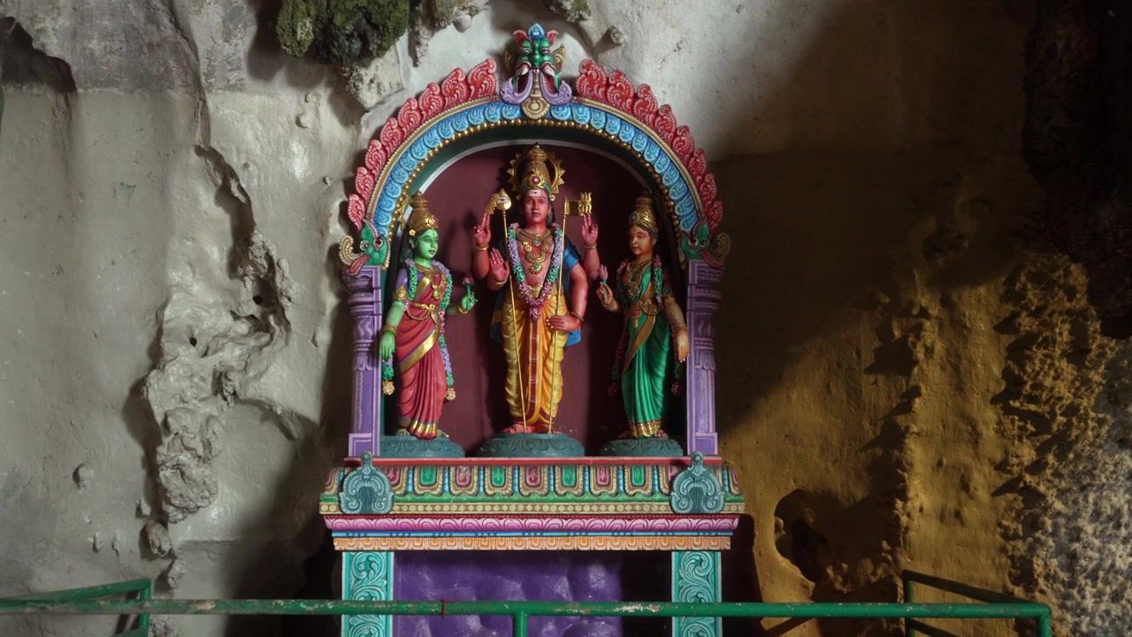 Close-up em movimento de figuras coloridas de divindades hindus colocadas dentro de um santuário em nicho de caverna.