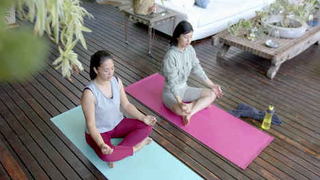 Fokussierte-Asiatische-Freundinnen-Praktizieren-Yoga-Meditation-Auf-Sonniger-Terrasse,-Zeitlupe