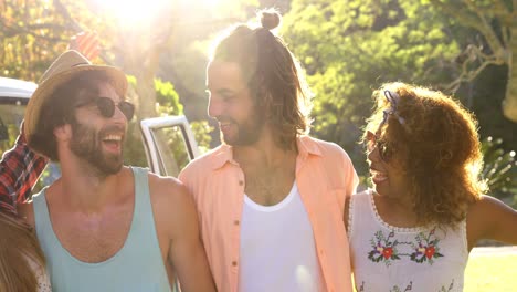 Smiling-hipster-friends-standing-in-front-of-the-van-