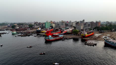 aerial drone shot flying over the buriganga river toward docked cargo ships in dhaka, bangladesh.