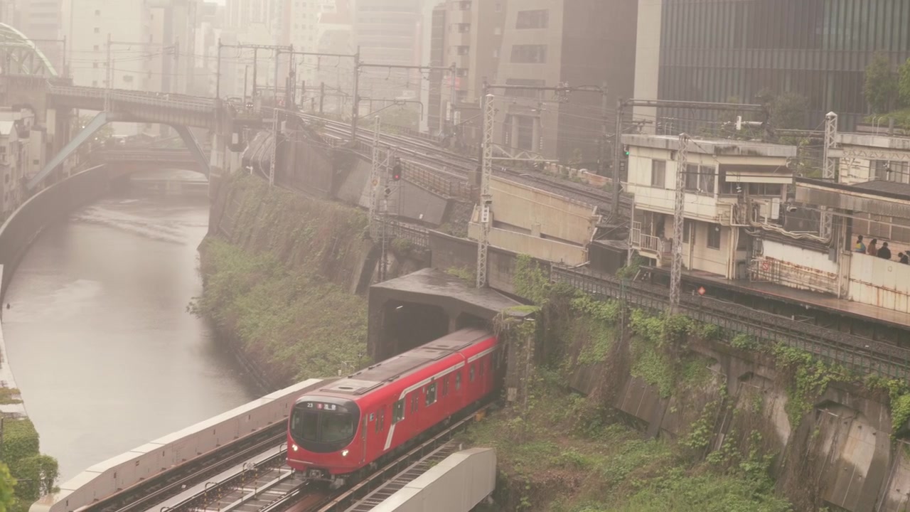Treno rosso della linea Marunouchi della metropolitana di Tokyo attraversa il ponte ferroviario in cemento sul fiume Kanda, dal ponte storico Hijiri-bashi a Ochanomizu, Tokyo, Giappone. Inquadratura dall'alto
