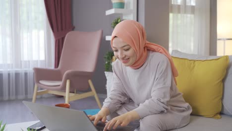 Muslimische-Junge-Frau-Schaut-Auf-Laptop-Und-Freut-Sich.