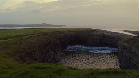 aerial shot gliding over the bridges of ross, revealing the unique cliff structure as water flows through.