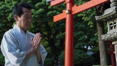 japanese man praying at a shrine