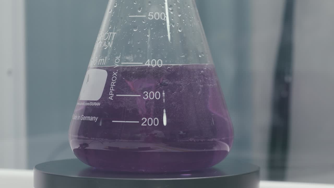 Stirring Test Tubes containing purple chemical liquids while working in a Modern Laboratory