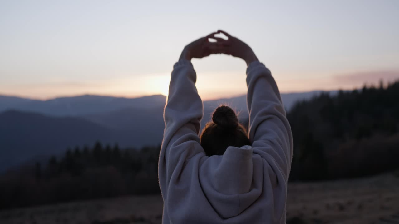 산에서 해가 지는 동안 스트레칭하는 여자