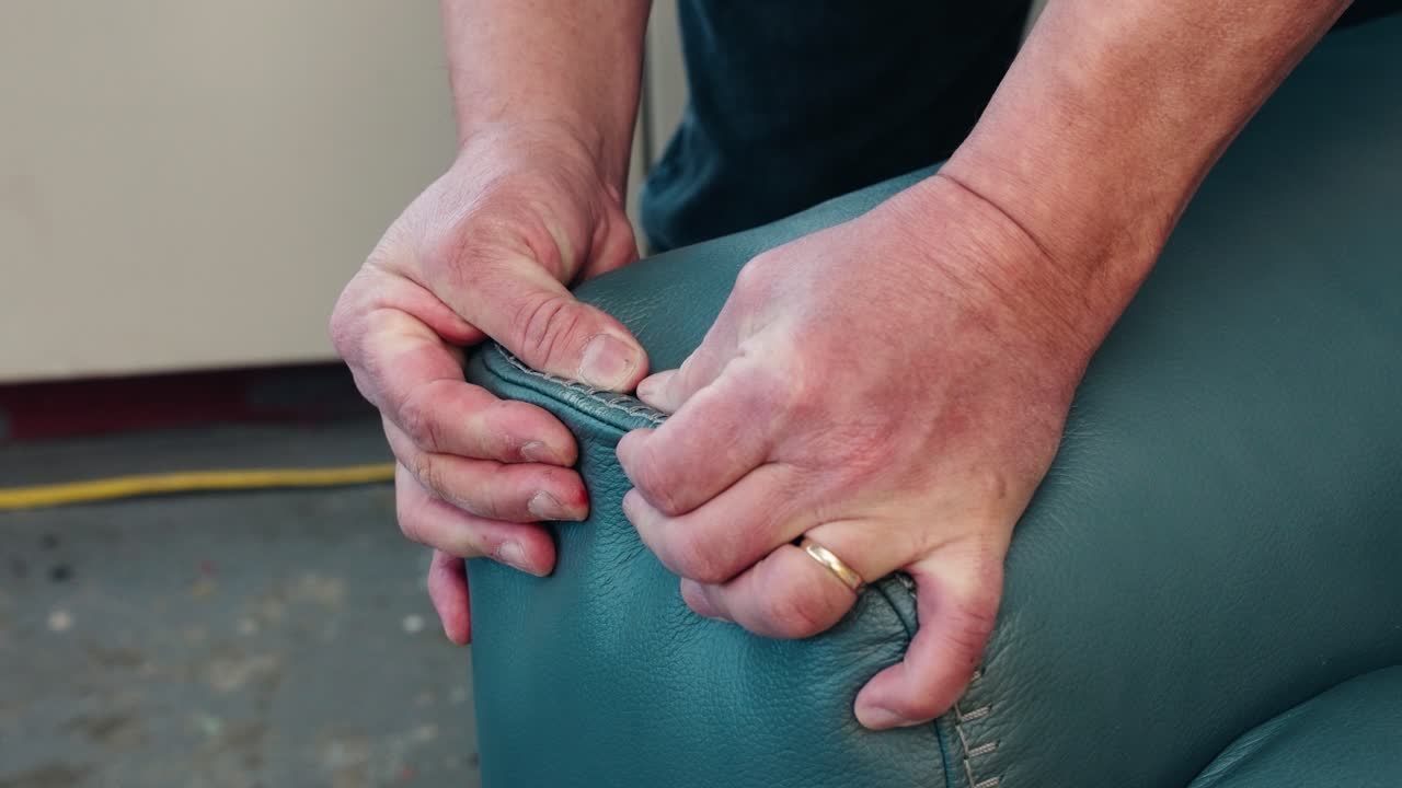 Hands knead and compress brown leather sofa corner, checking suppleness