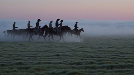 cowboys on horses in a misty field