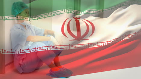 composición digital de la bandera de irán ondeando contra una trabajadora de salud caucásica estresada en el hospital