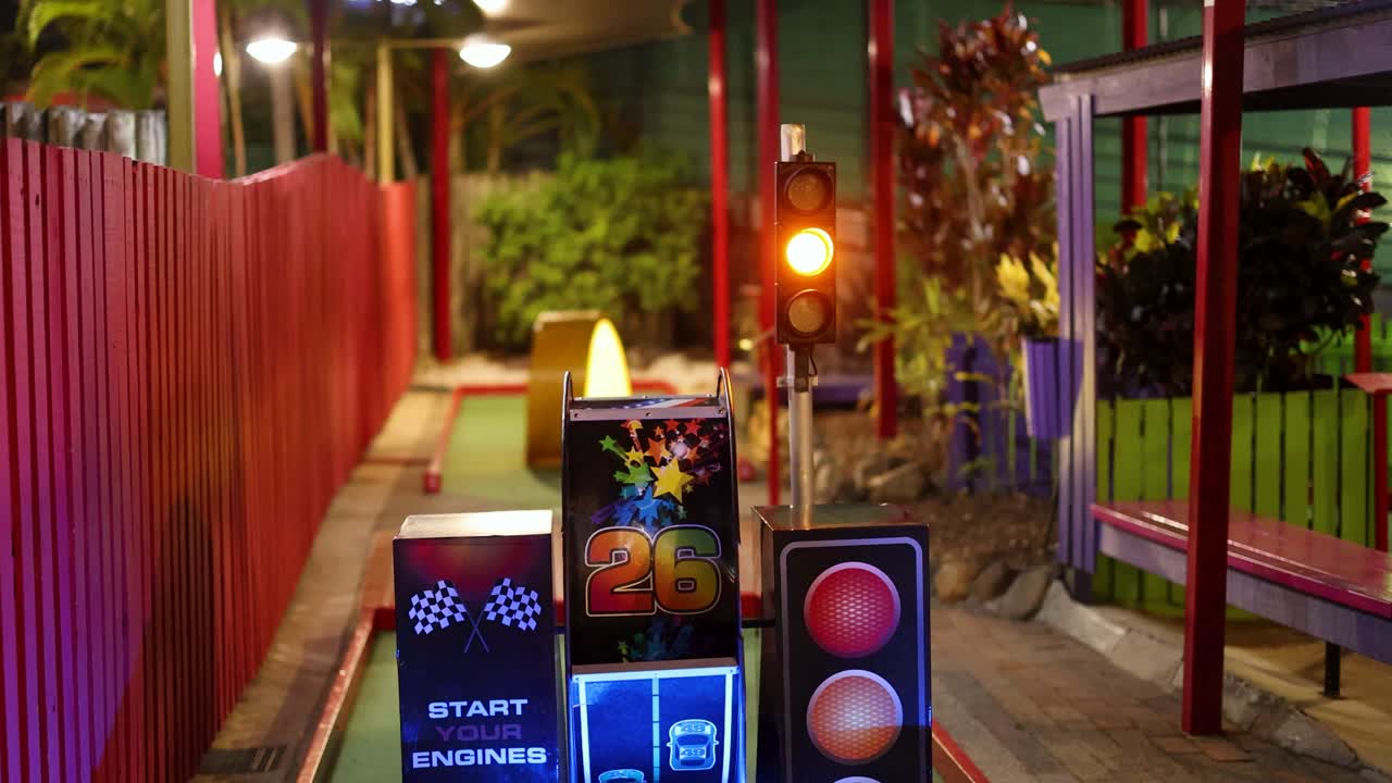 A colorful miniature golf course with dynamic light displays and digital scoreboards, creating an engaging and lively atmosphere