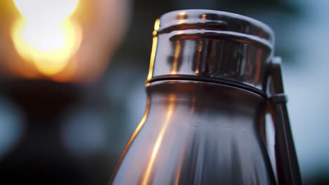 a glowing metal water bottle captured in a stunning close-up with soft backlighting, highlighting its smooth surface and reflections in a serene environment.