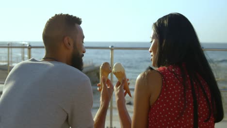 un couple de race mélangée souriant à l'autre avec leurs cônes de glace 4k