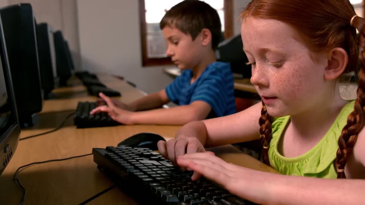 Little girl using computer in classroom in school