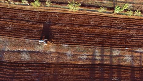 Aerial-clip-of-a-tractor-that-moves-on-a-red-field-in-Karatu-town-area,-Tanzania