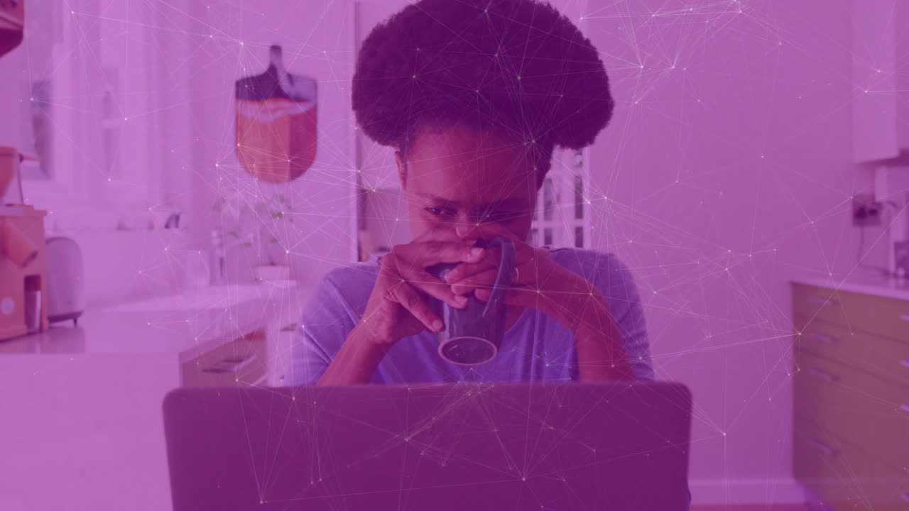 Woman working remotely in kitchen holding mug, using laptop with animated business charts